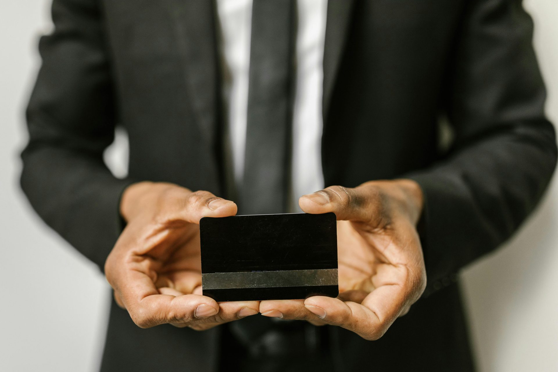 Close-up of a businessman holding a blank credit card with both hands, emphasizing finance.