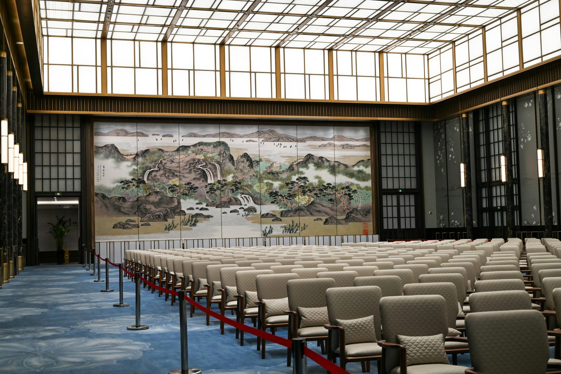 Grand hall with rows of chairs and large mural